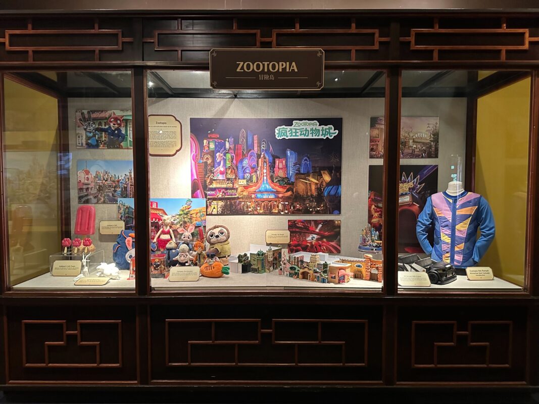 A display window showcasing "Zootopia" merchandise, including plush toys, figurines, apparel, and themed artwork against a backdrop of city scenes from the animated film.