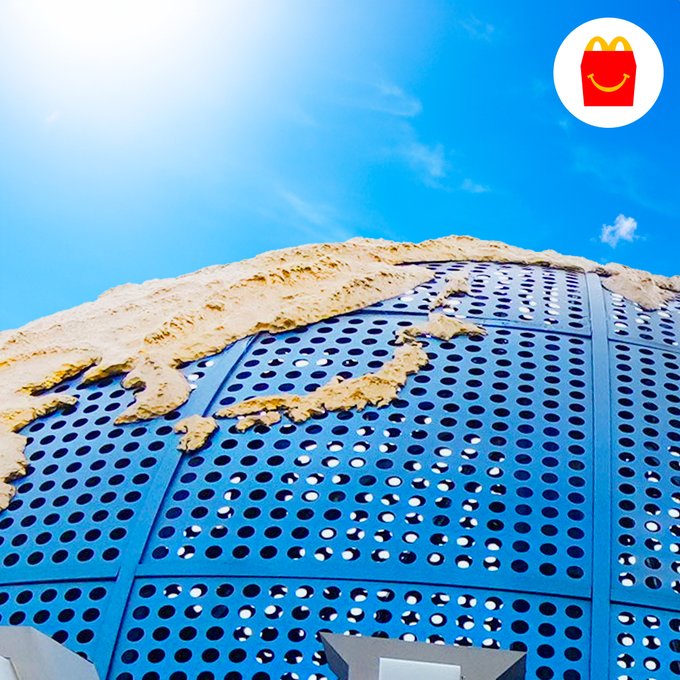Close-up of a globe sculpture under a bright sky, highlighting the continents. A shopping bag logo appears at the top right corner.