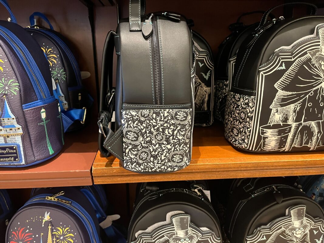 A display shelf holding black and white themed backpacks featuring various intricate patterns and designs, including fireworks and a castle image.