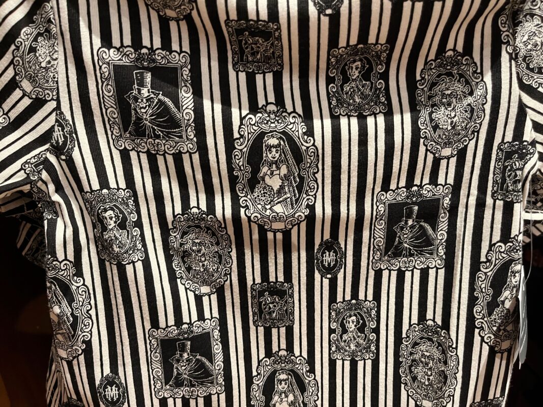 Black and white fabric featuring a striped pattern with Victorian-style framed portraits and ornate designs.