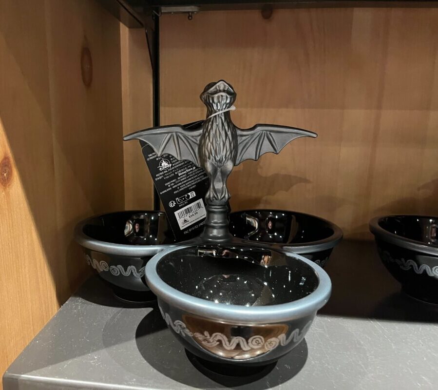 Several black bowls with swirling patterns are displayed on a shelf. A decorative item resembling a bat is placed in one of the bowls.