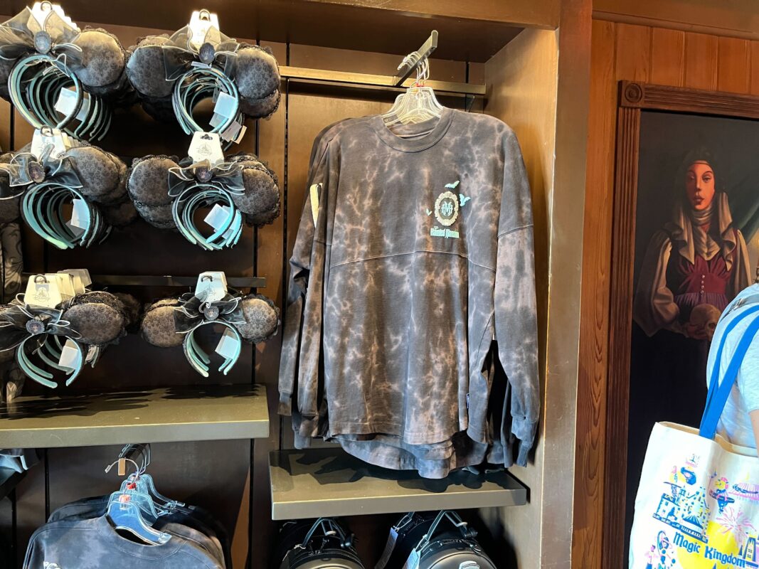 A display of dark tie-dye long-sleeve shirts and Mickey Mouse ear headbands on shelves in a retail store.