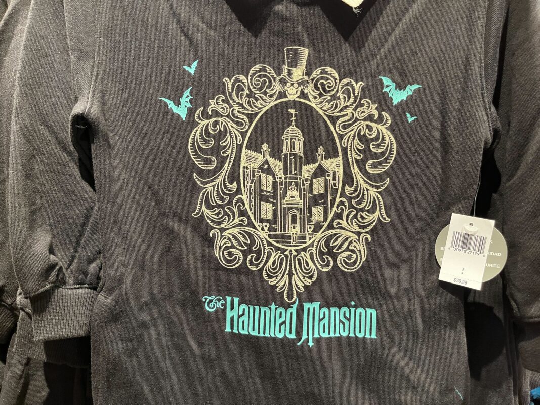 A black sweatshirt featuring a detailed illustration of a mansion with ornate design elements and text reading "The Haunted Mansion." There are also two bats and a price tag attached.
