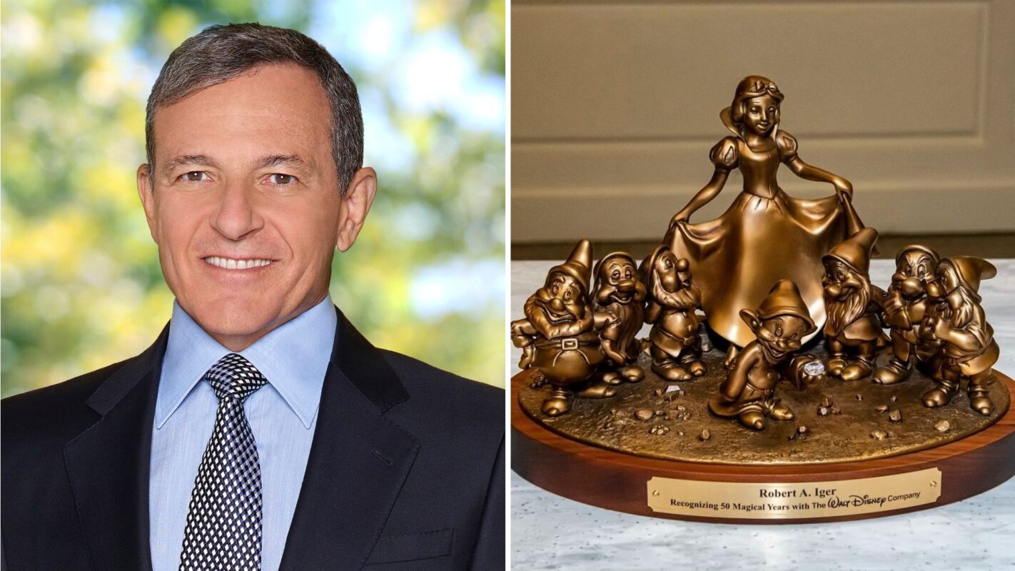 A man in a suit and tie is on the left. On the right is a bronze statue depicting Snow White and the Seven Dwarfs with an engraved plaque.