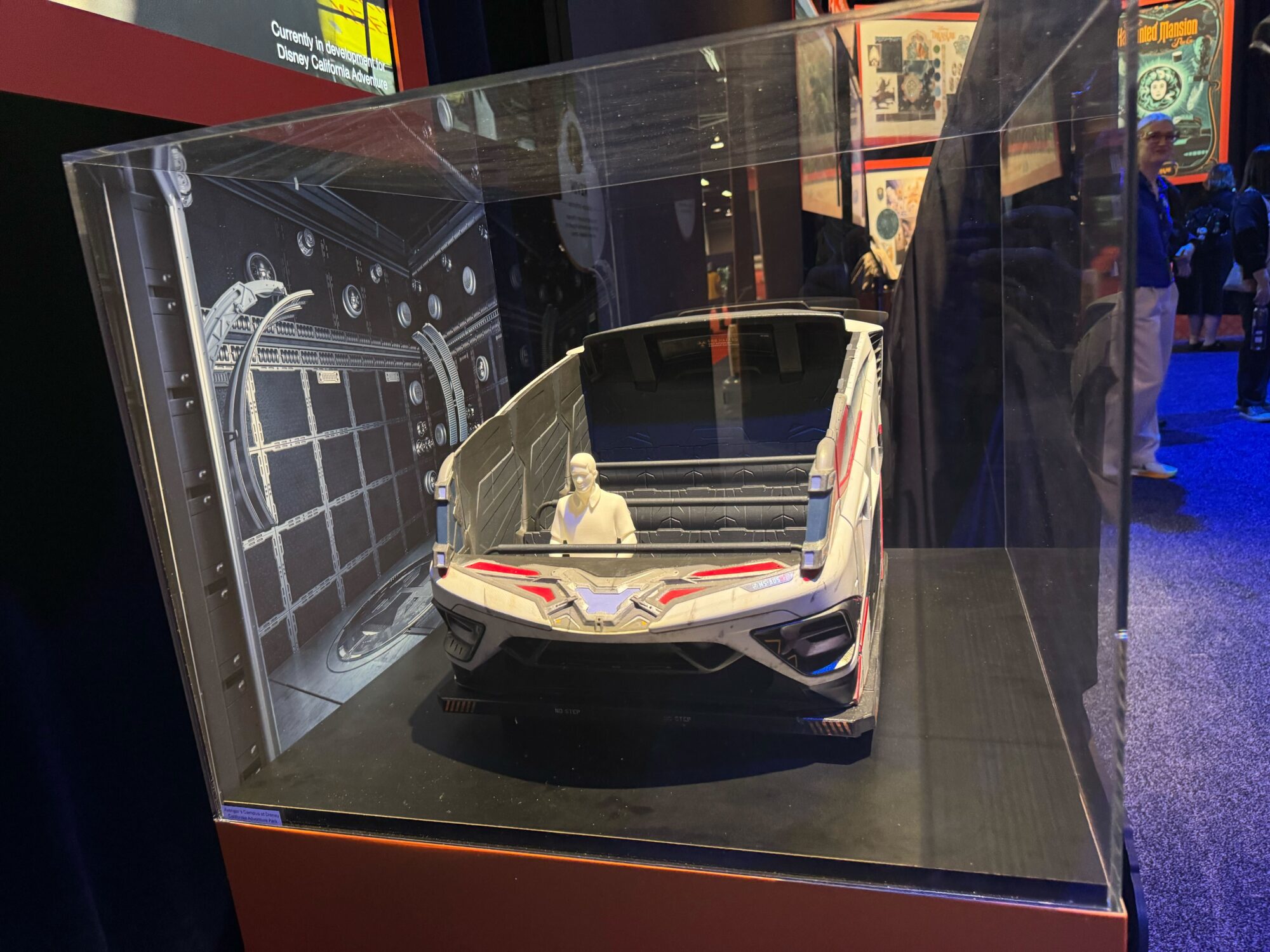 A detailed, futuristic vehicle model featuring Avengers King Thanos with a small humanoid figure inside is displayed in a clear protective case at the Disney California Adventure exhibition booth.