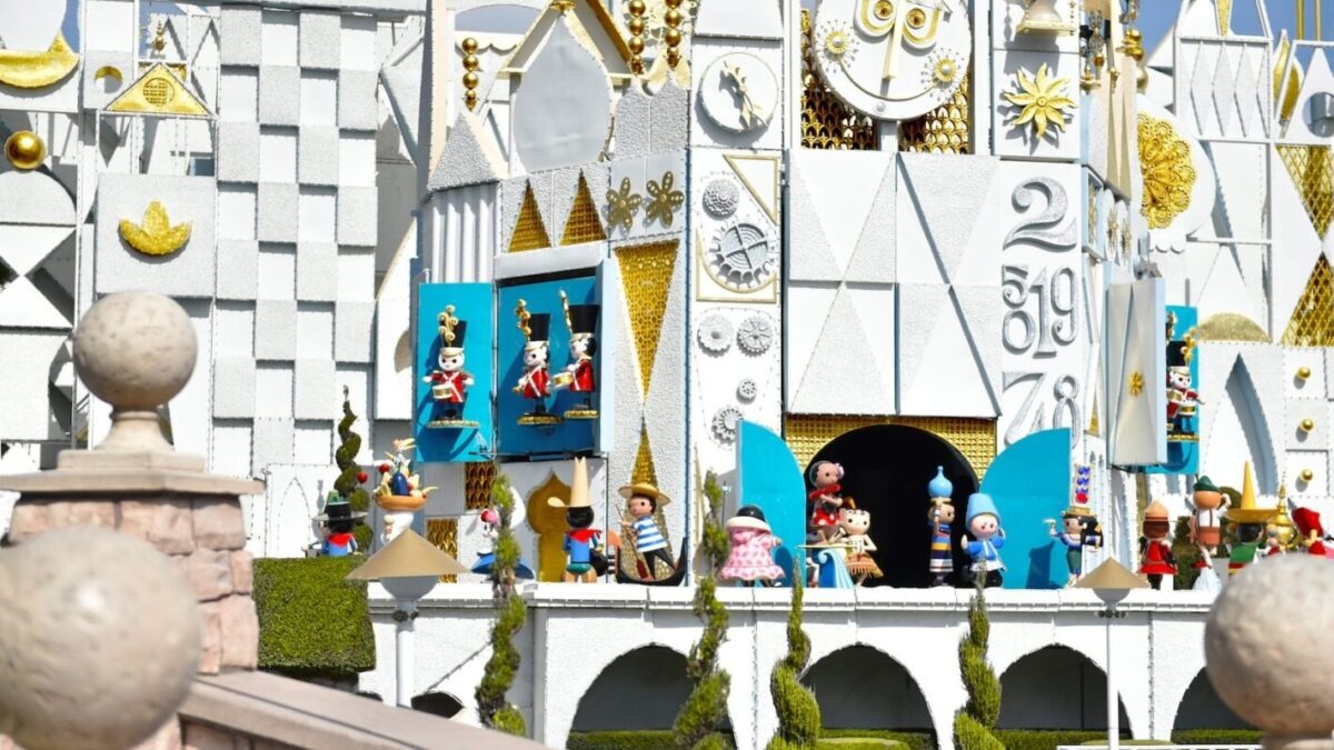 A whimsical facade with animated figures and a clock tower is showcased, reminiscent of the iconic "It's a Small World" attraction at Disneyland.