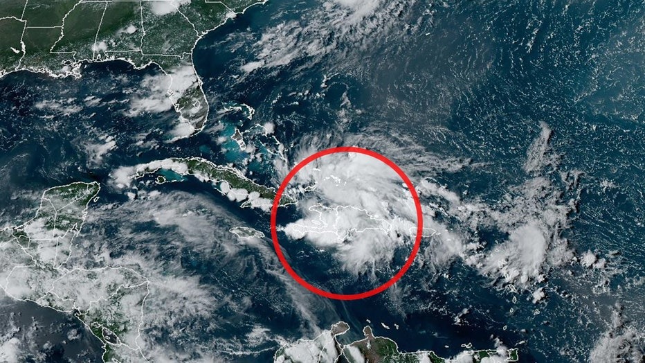 Satellite image showing cloud formation over the Caribbean region, with a red circle highlighting a specific weather disturbance that has triggered a State of Emergency.