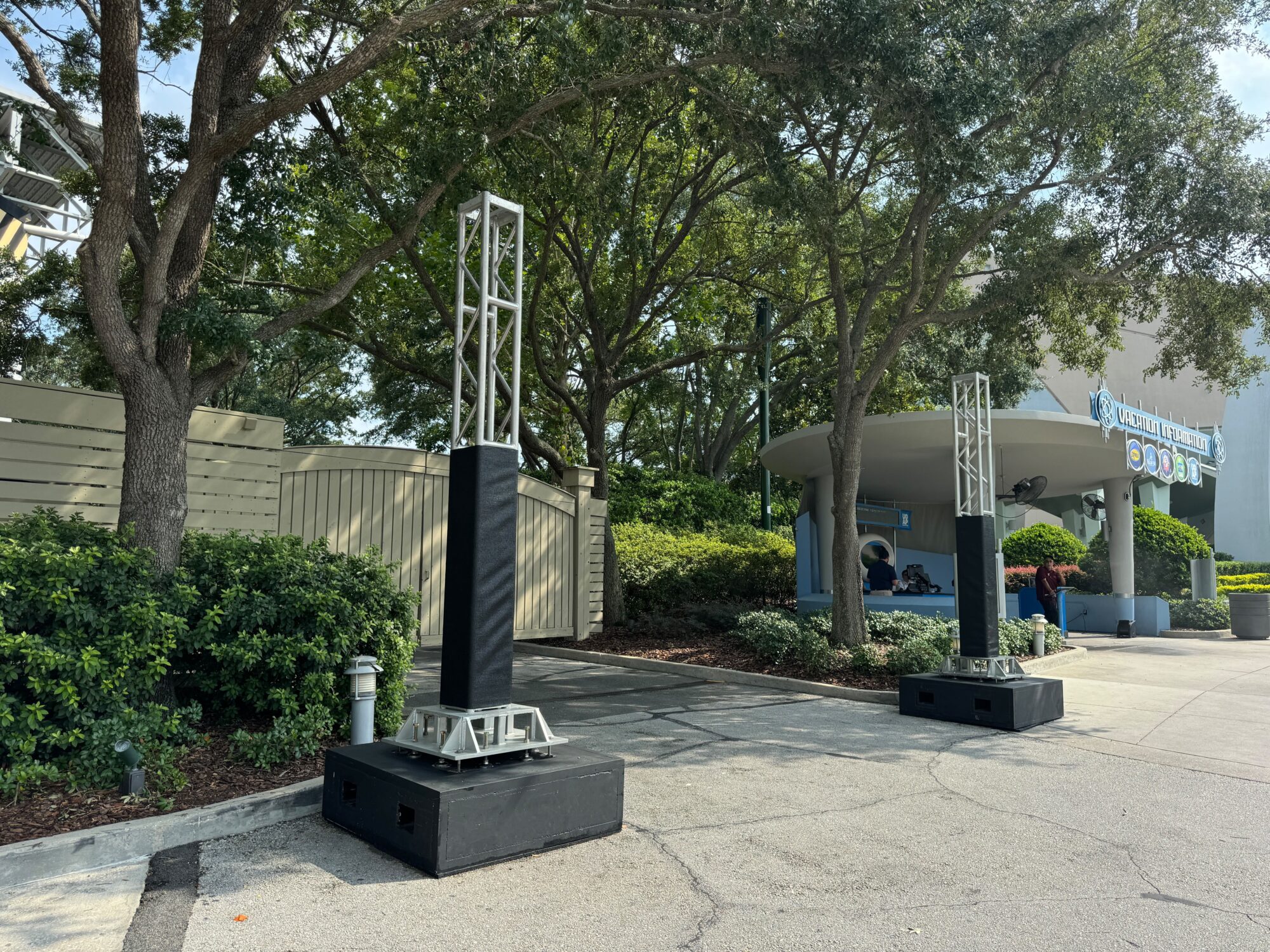 Two large, black speakers are set up outside a building entrance surrounded by greenery, transforming the area into an impromptu scare zone.