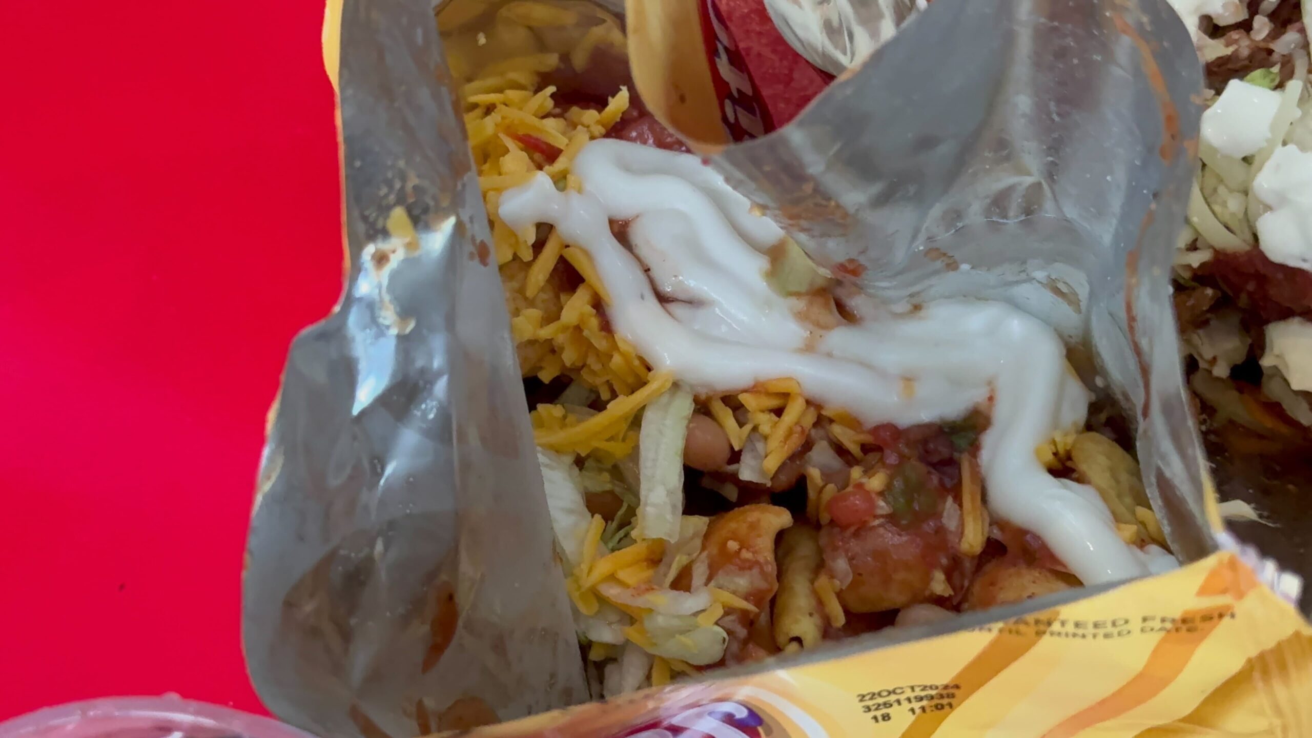 A bag of chips is cut open and filled with toppings, including shredded cheese, sour cream, and diced vegetables—perfect for a quick bite at Halloween Horror Nights.