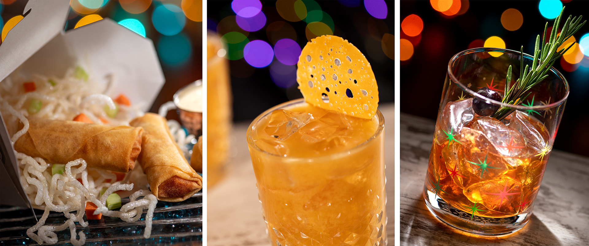 A meal consisting of spring rolls and crispy noodles is pictured next to two cocktails, one with a garnish and the other with a sprig of rosemary. Multicolored bokeh lights are in the background, evoking the festive spirit of Disney Jollywood Nights.