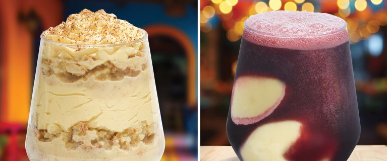 Two glasses with delectable treats: one filled with layered cake and cream, the other with a dark purple beverage featuring cream swirls. Both mouthwatering delights are set against a colorful, blurred backdrop, making them perfect for celebrating Hispanic and Latin American Heritage Month at Disneyland.