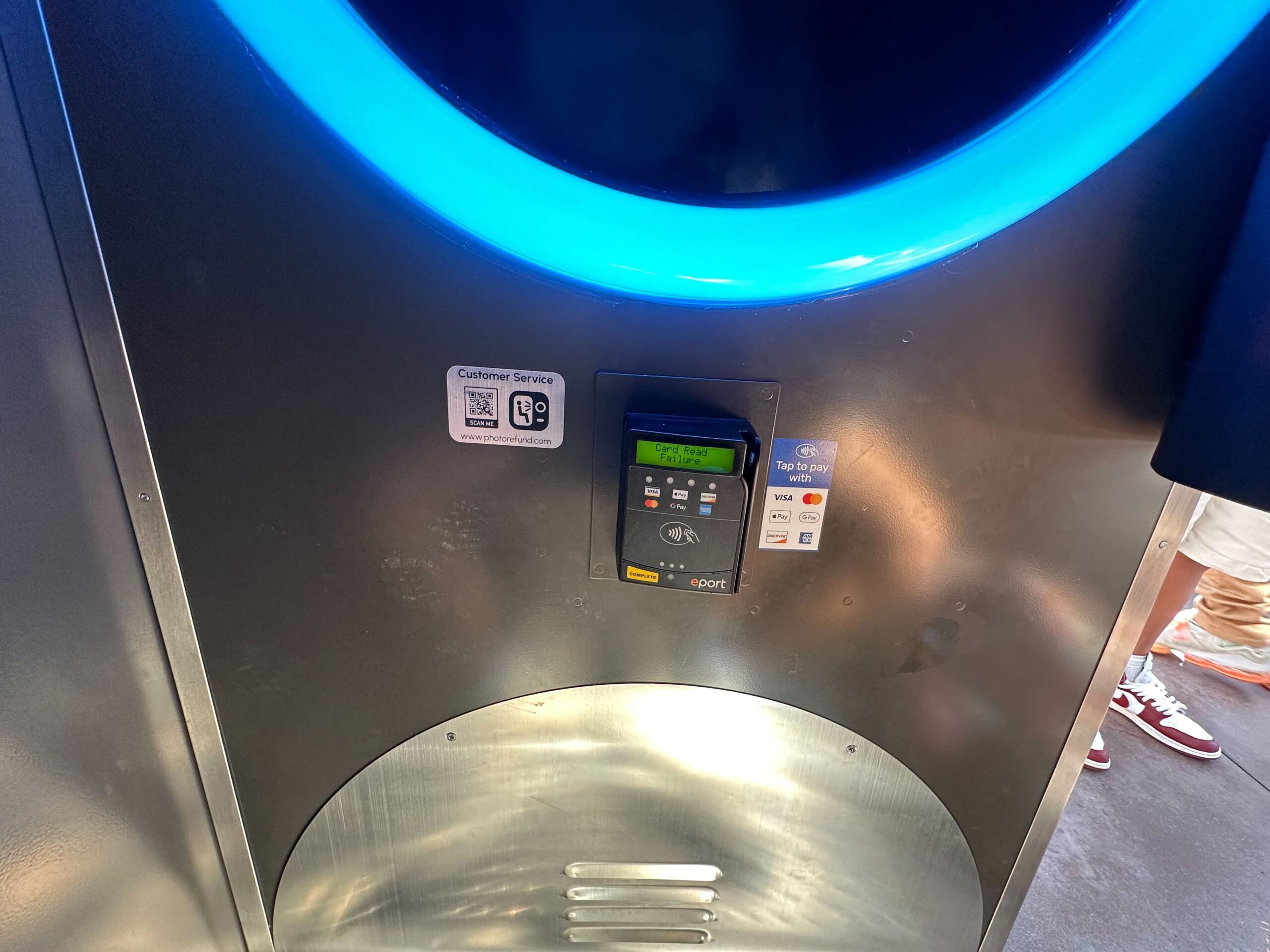 A large, round metallic appliance with a digital control panel and buttons. A blue light encircles the upper section.