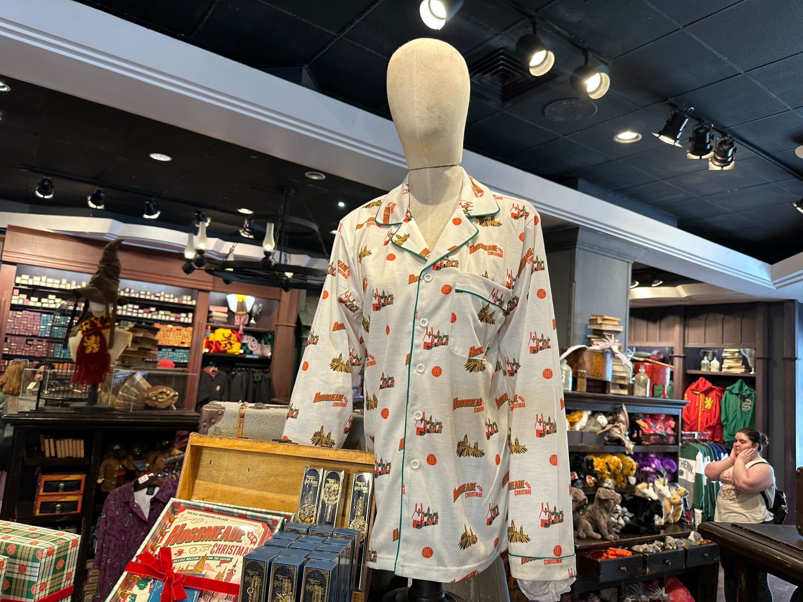A mannequin sports a long-sleeve shirt adorned with a deer and "Prongs" pattern, reminiscent of Hogsmeade's magical allure. In the background, shelves brim with various enchanting merchandise. A mannequin sports a long-sleeve shirt adorned with a deer and "Prongs" pattern, reminiscent of Hogsmeade's magical allure. In the background, shelves brim with various enchanting merchandise.