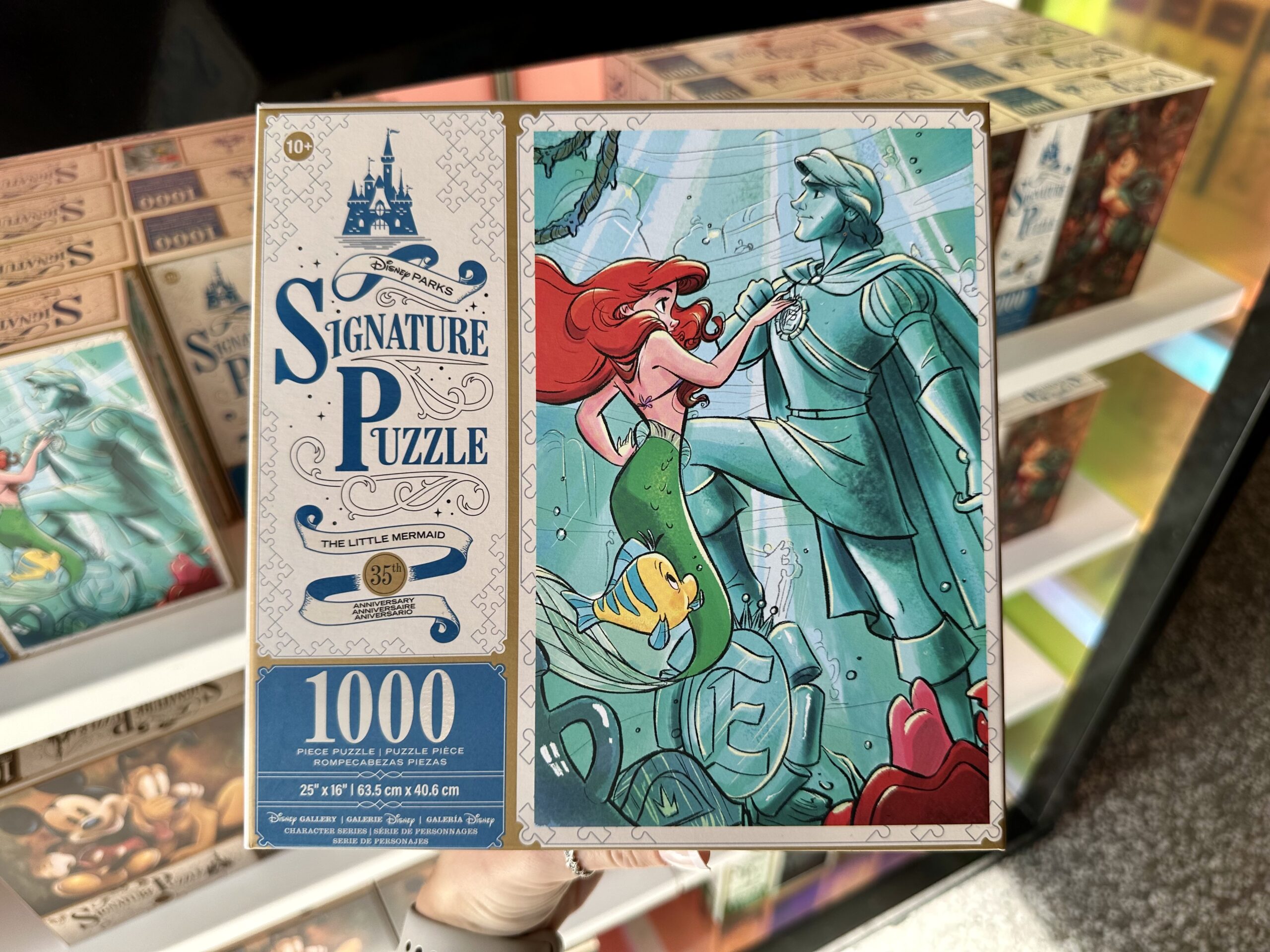 Box of a 1000-piece puzzle featuring characters from "The Little Mermaid" with Ariel and a statue underwater.