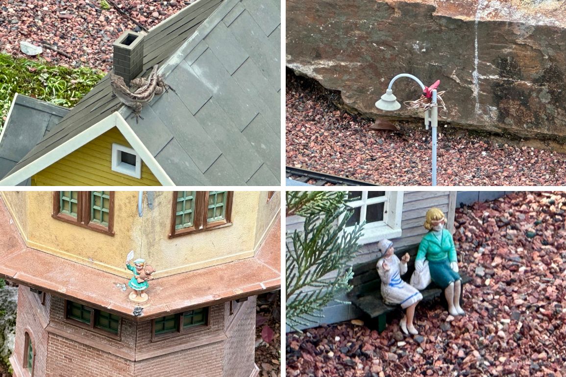 Miniature scenes of buildings and figures, including a house with a bird's nest, a lamppost with a nest, a fairy on a roof, and two women sitting on a bench.