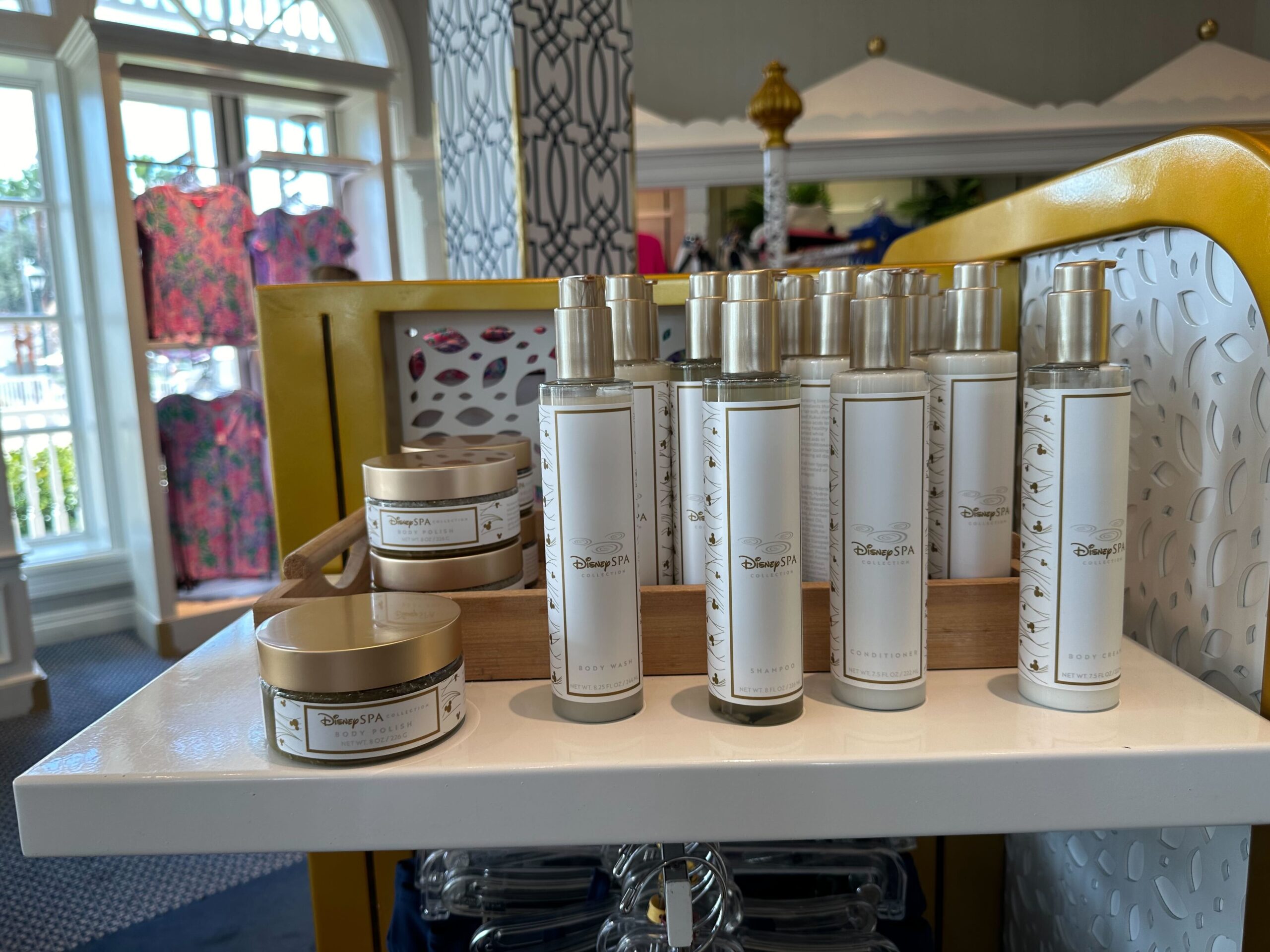 A charming display of Disney-branded fragrance bottles and creams sits on a wooden shelf in the store, reminiscent of the Grand Floridian's elegant merchandise offerings.