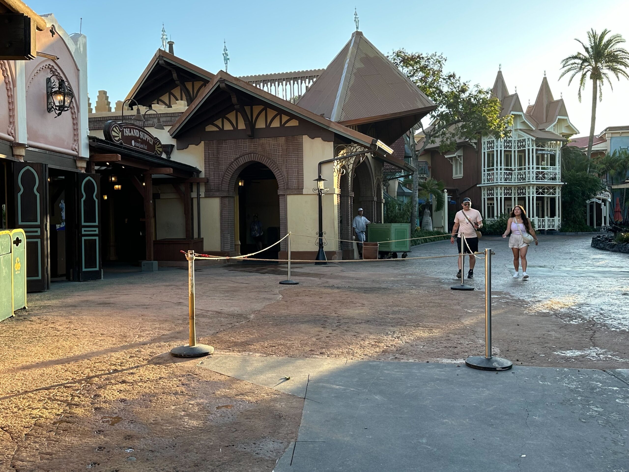 Outside of a closed theme park attraction with roped-off entrance and a few people walking by in the background.