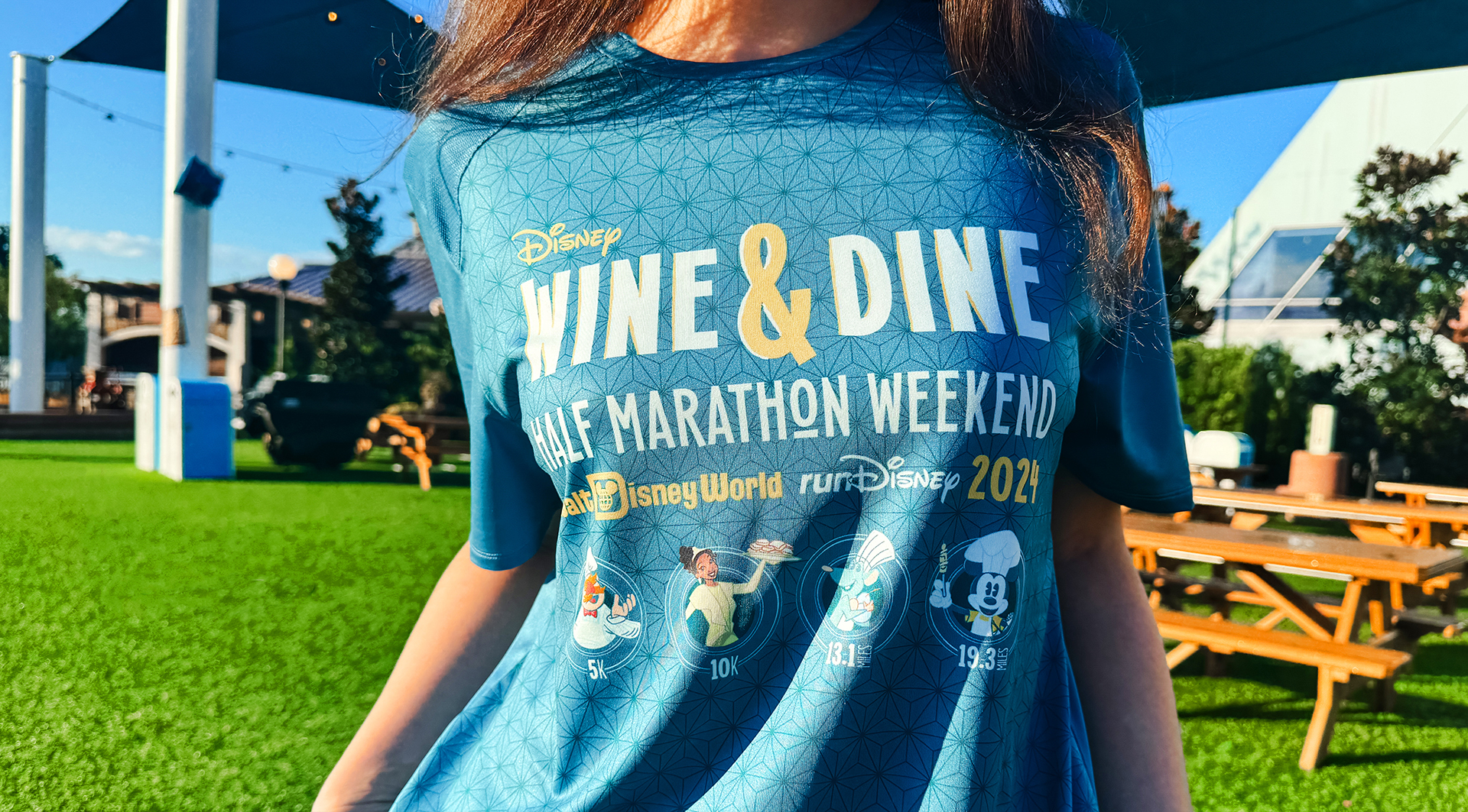 Person wearing a blue shirt with "Disney Wine & Dine Half Marathon Weekend" and images of Disney characters depicting different race distances.