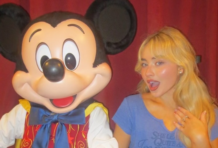 A person posing playfully with a Mickey Mouse character.