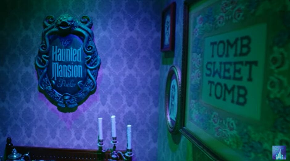 Wall with a plaque reading "Haunted Mansion" aboard the Disney Treasure Cruise Ship, adorned with "Tomb Sweet Tomb" framed art. Three unlit candlesticks rest on a table beneath, adding an eerie charm to the maritime adventure.
