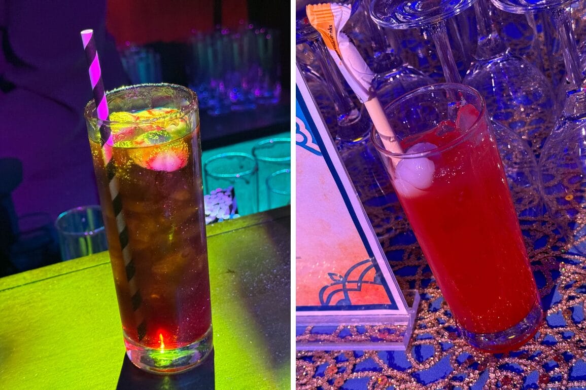 Two glasses with drinks on a bar; left glass has a dark beverage with ice and a striped straw, right glass contains a red drink with a stir stick and lychee garnish.