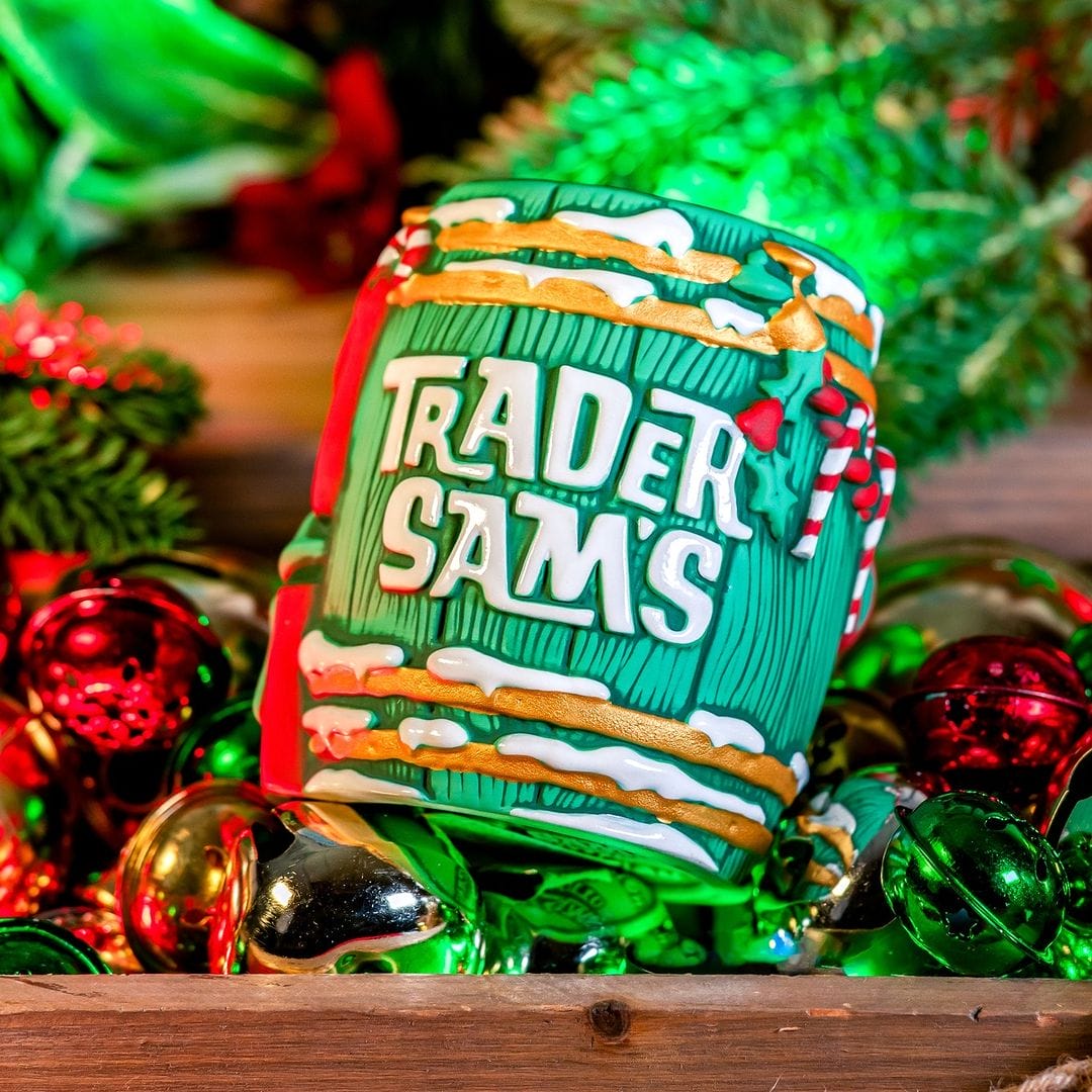 A decorative mug labeled "Trader Sam's" sits among festive Christmas ornaments and greenery.