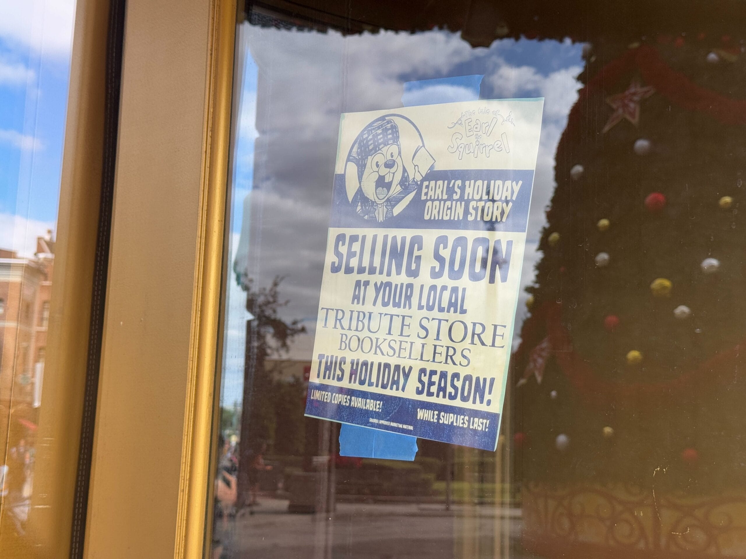 A poster on a glass door advertises "Earl's Holiday Origin Story" selling soon at local tribute store booksellers this holiday season.