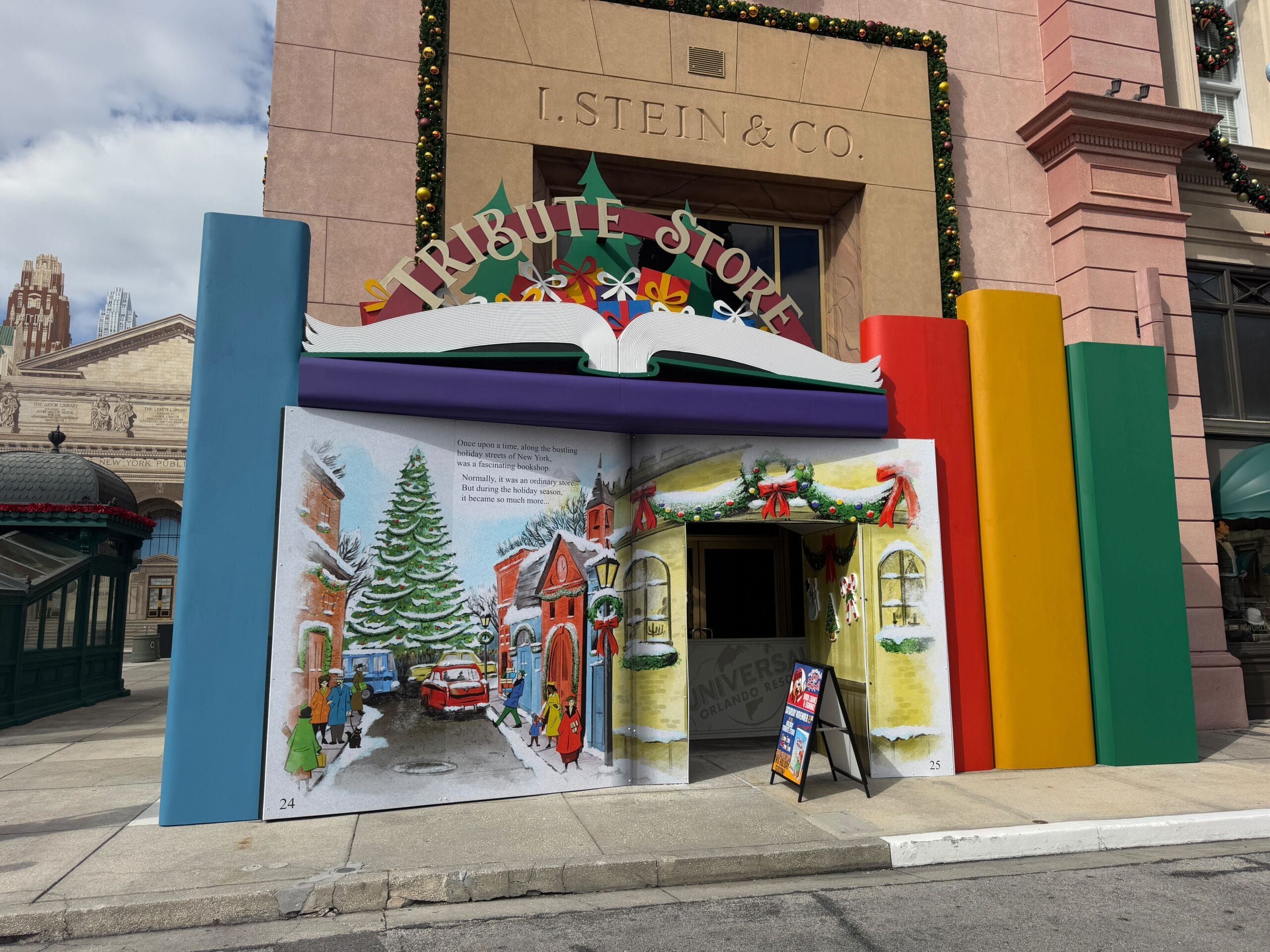Holiday-themed storefront with a book-like entrance, featuring winter illustrations and decorations. Text reads "Tribute Store" on the facade.