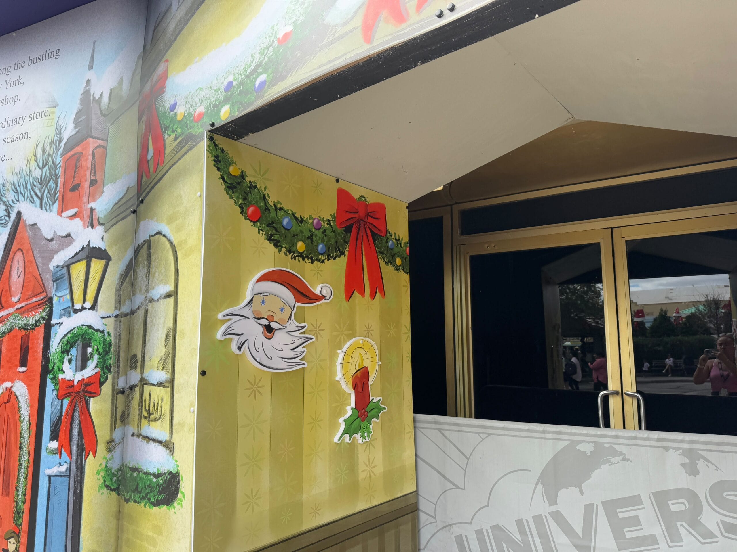 Entrance decorated with Christmas-themed wall art featuring Santa Claus, a red bow, and greenery.