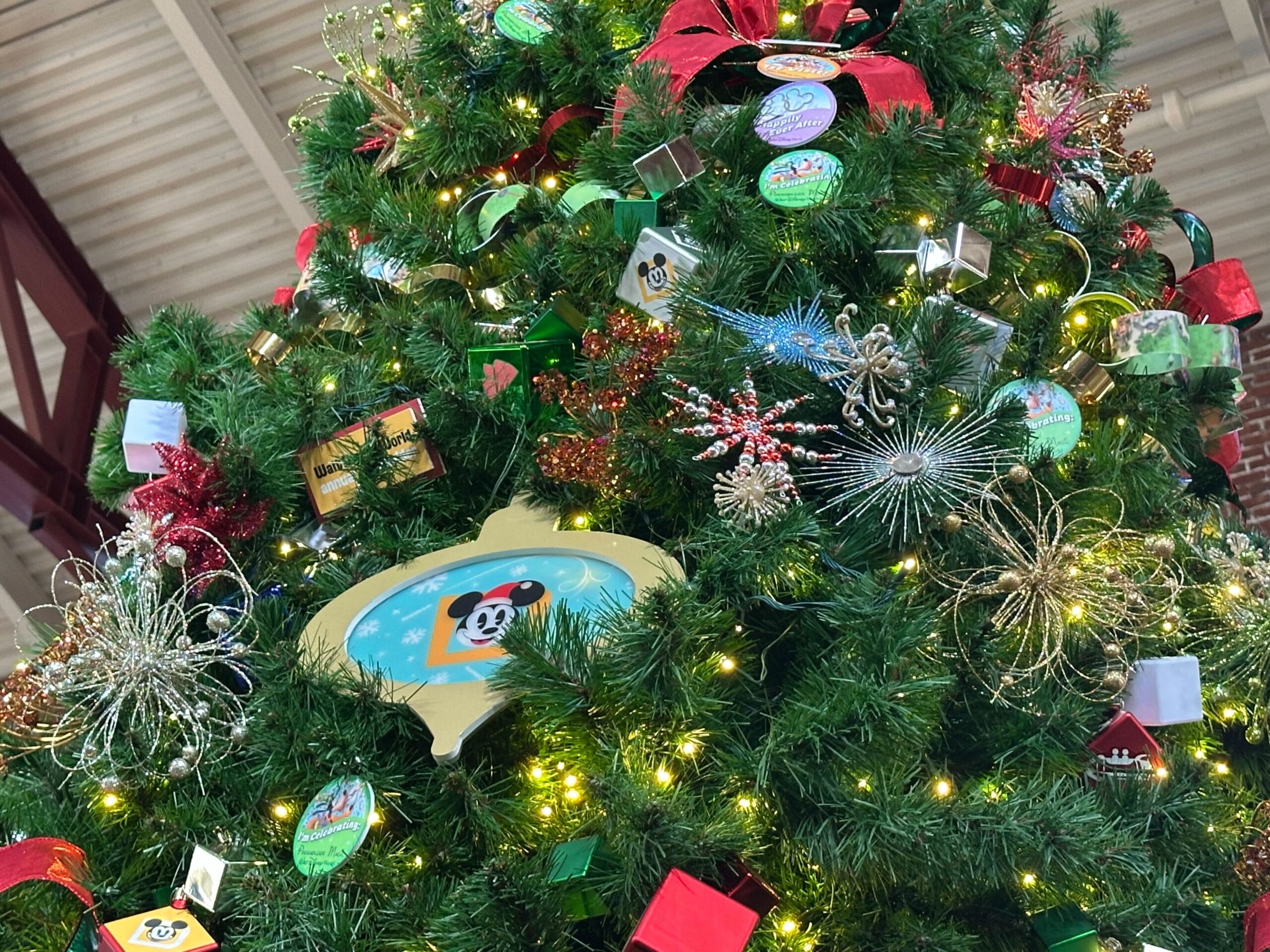 Close-up of a decorated Christmas tree with various ornaments, including a large yellow bauble featuring a cartoon panda, surrounded by lights and ribbons.