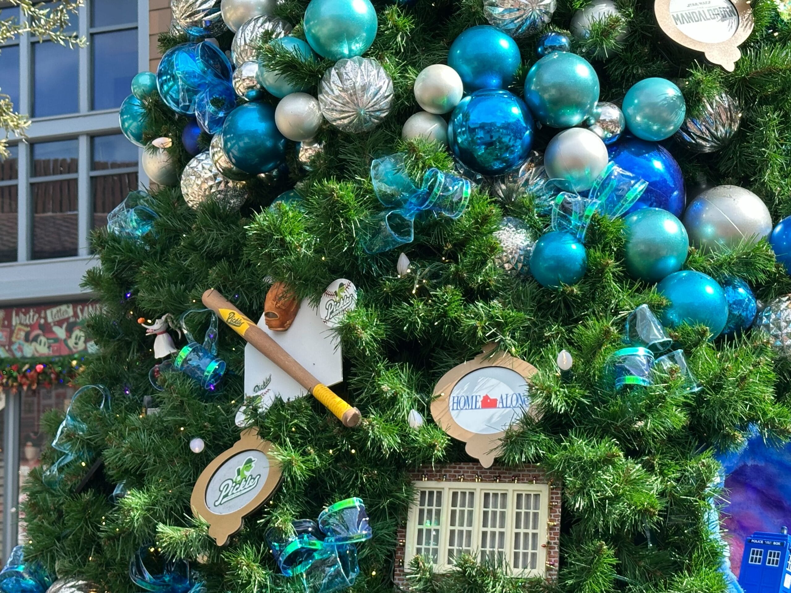 Christmas tree decorated with blue and silver baubles, baseball-themed ornaments, a bat, and various signs.