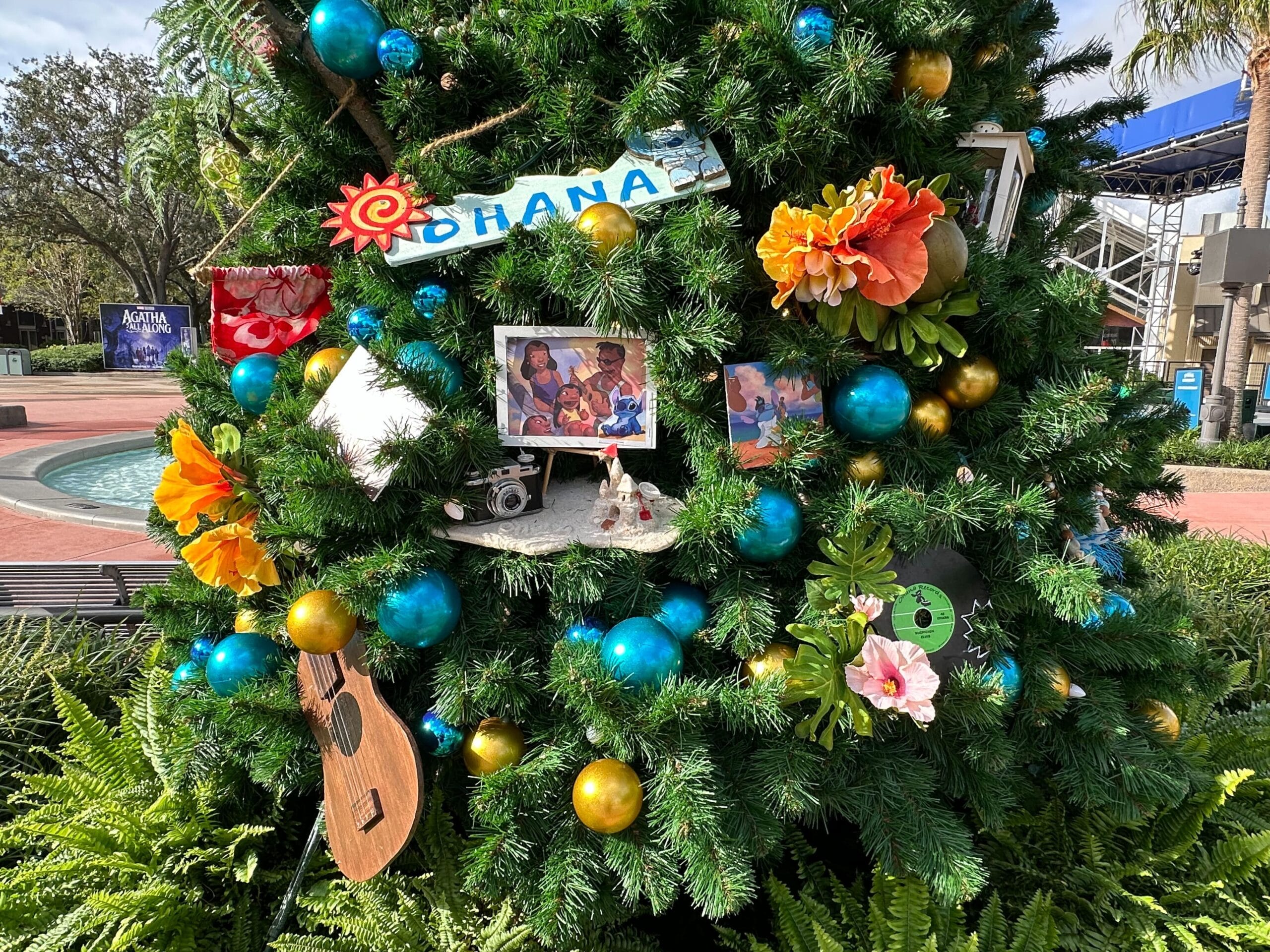 Christmas tree decorated with family photos, flowers, a ukulele, and colorful ornaments, including a sign that reads "Ohana.