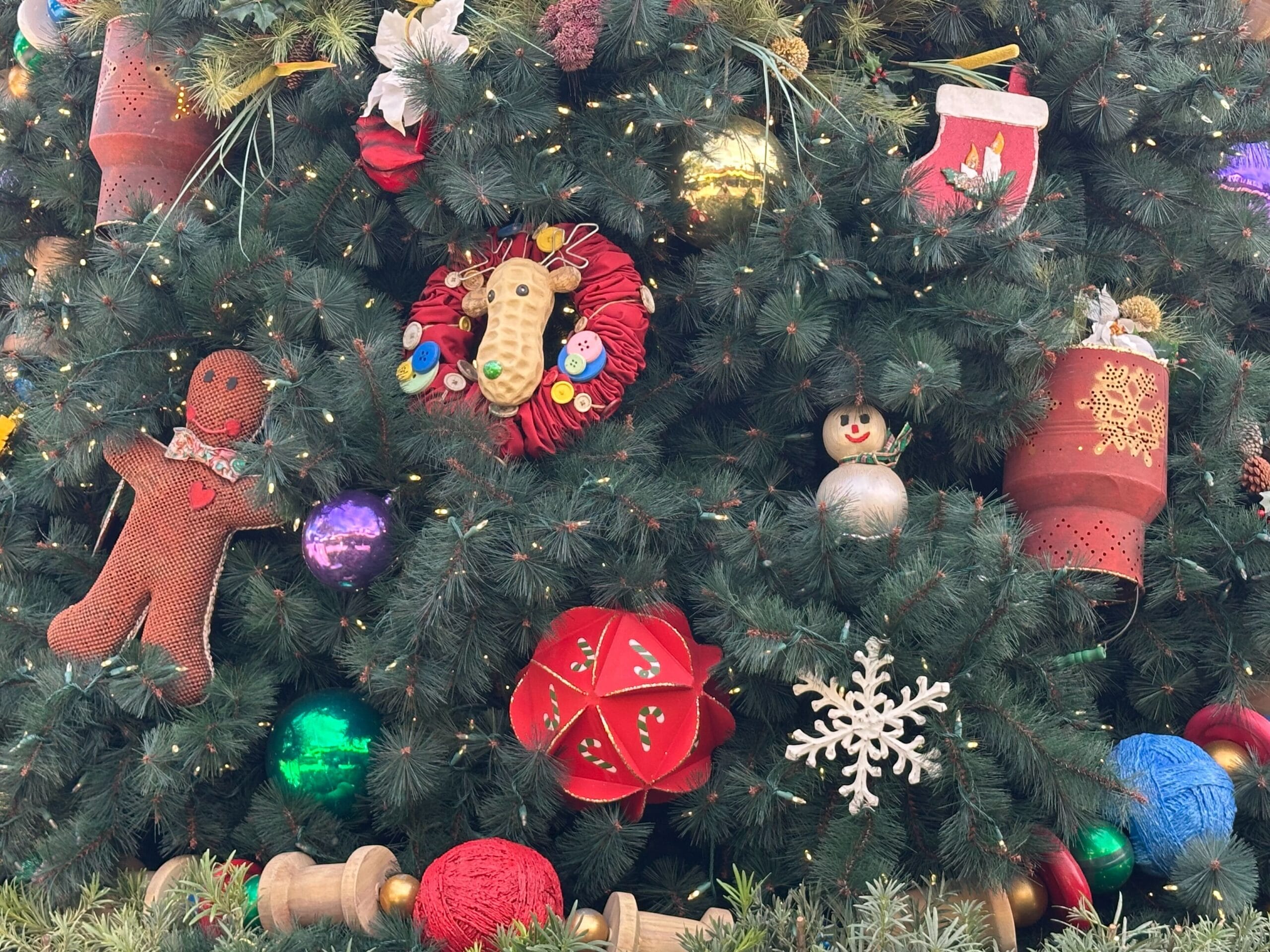 Christmas tree decorated with a gingerbread man, multicolored ornaments, a stuffed horse head, a snowflake, and a stocking.
