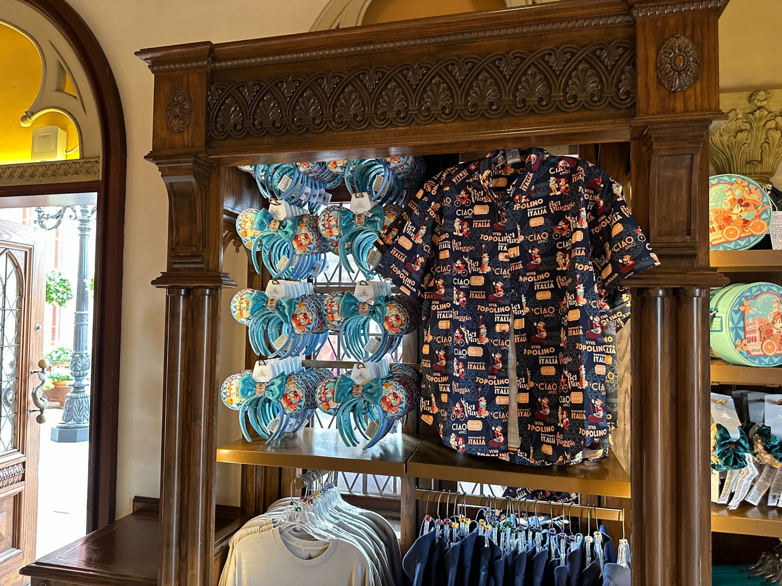 Merchandise display with a shirt featuring colorful text and graphics, headbands on the left, and additional clothing items below on a shelf.
