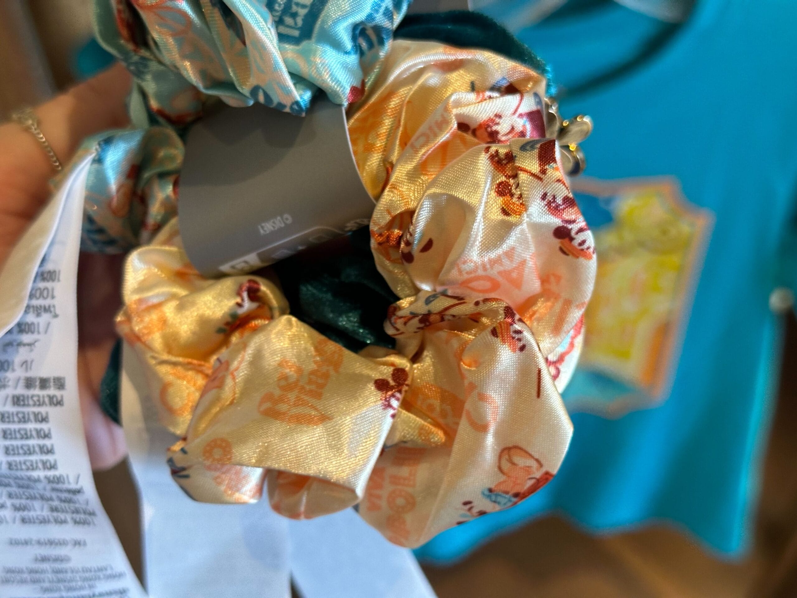 Close-up of a hand holding colorful hair scrunchies with various patterns.