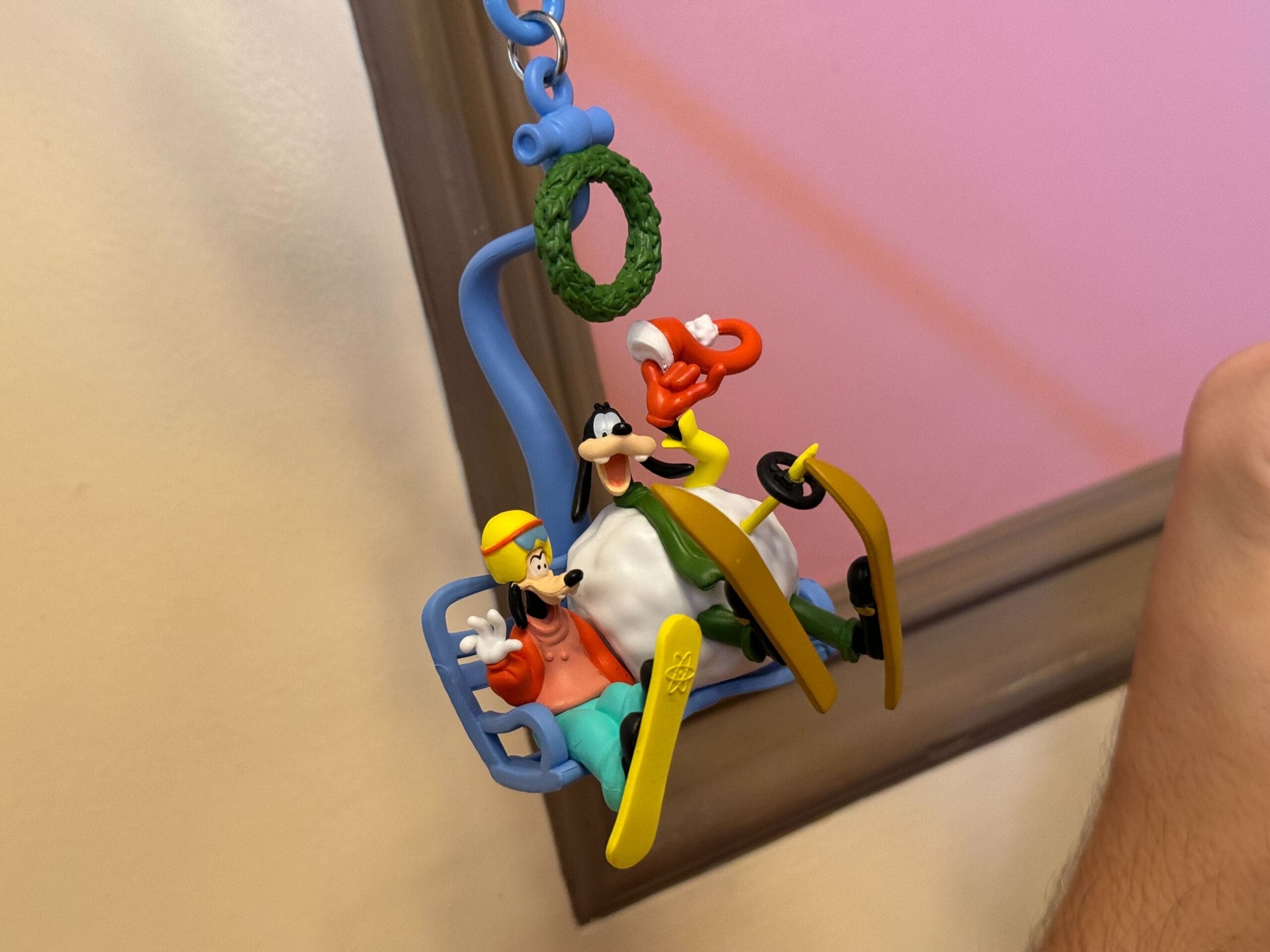 Three cartoon characters, including Goofy & Max, are on a ski lift-themed ornament, adorned with a wreath at the top and featuring a playful ski straw clip.