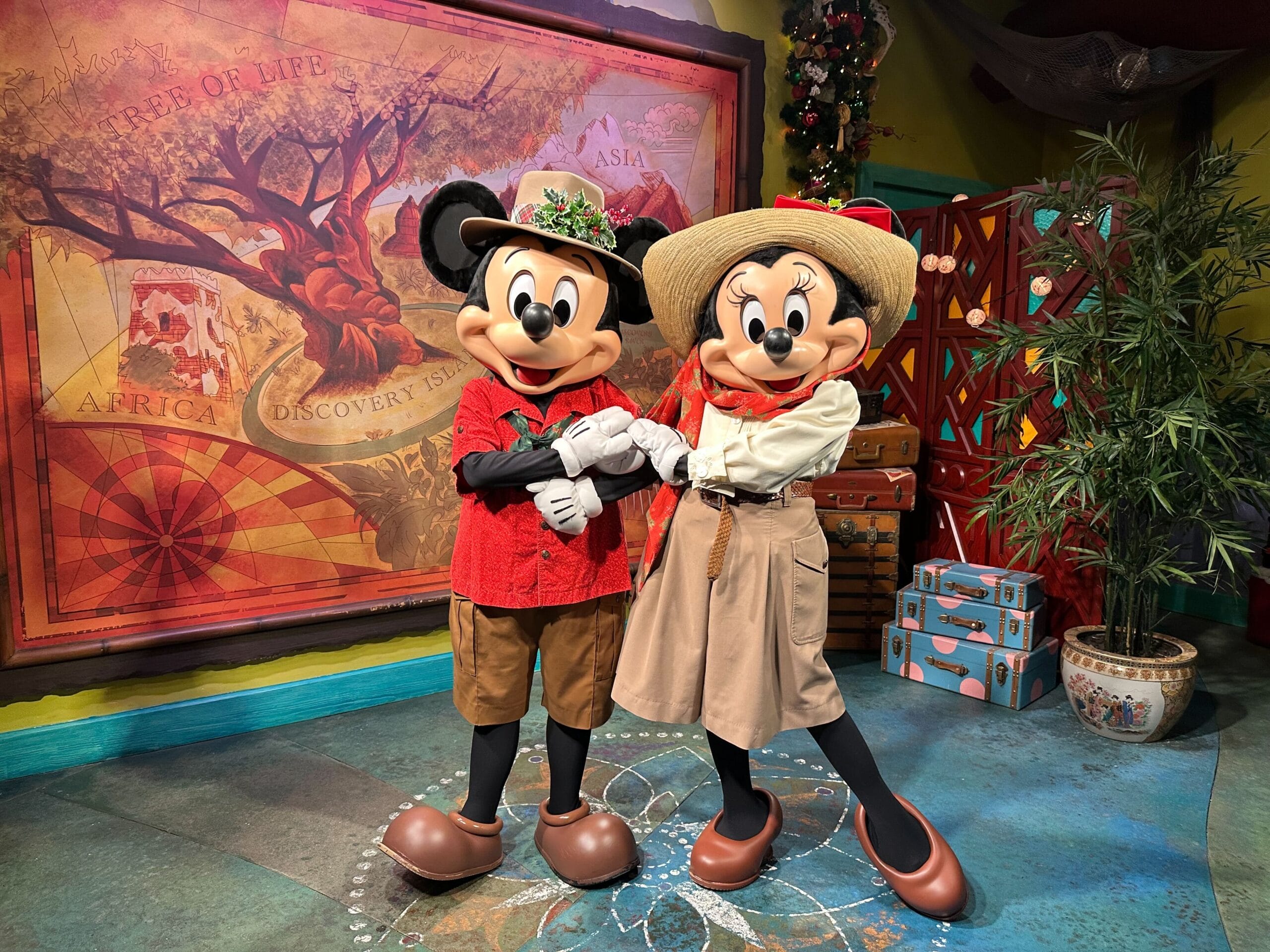 Mickey and Minnie Mouse, dressed in their best holiday outfits, stand hand in hand in front of a map-themed wall at Disney's Animal Kingdom, exuding adventure and charm.