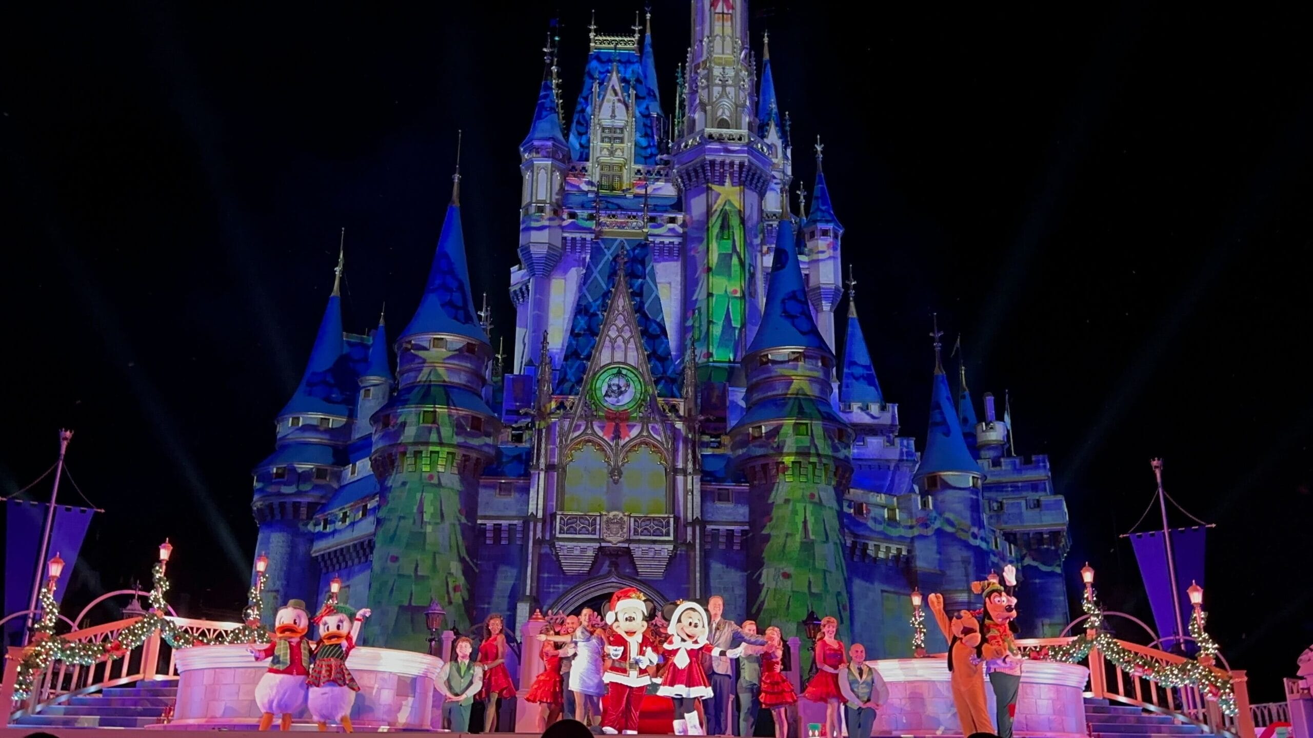 The Disney castle dazzles under the night sky, hosting the most merriest celebration. Characters and performers enchant the stage in festive costumes, creating a magical spectacle.