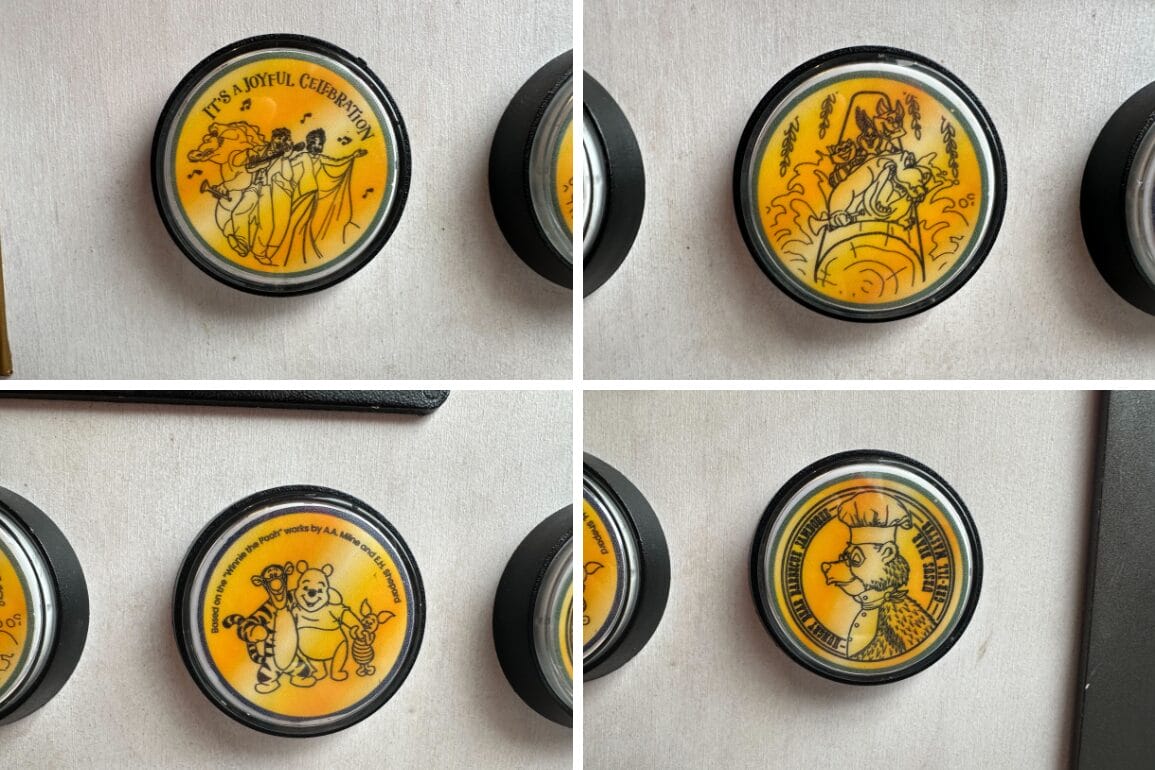Four round pins featuring yellow and black designs of various cartoon characters and festive scenes.