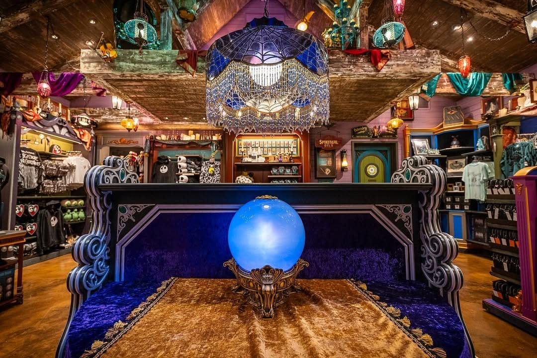 A richly decorated room serves as the perfect setting for your daily recap, featuring a central glowing blue crystal ball on a table. The space boasts ornate furniture, hanging lamps, and shelves brimming with various items.