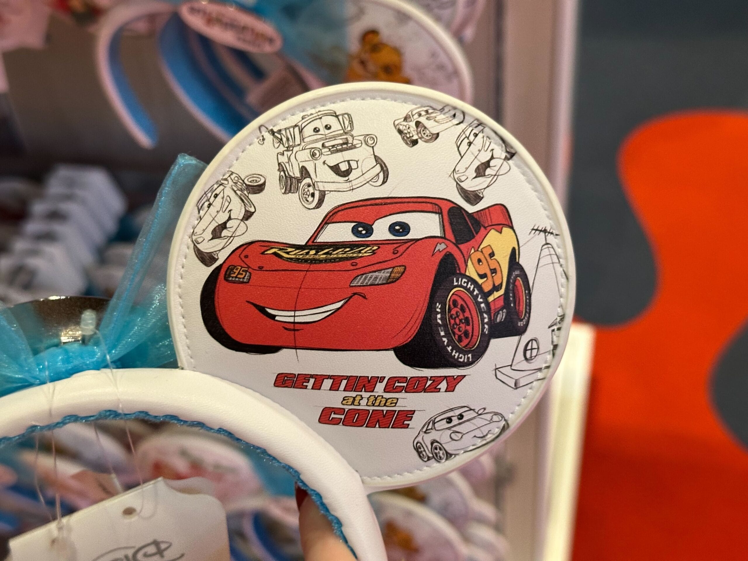 Merchandise featuring a red animated race car and the text "Gettin' Cozy at the Cone" with a car-themed design on a round item.