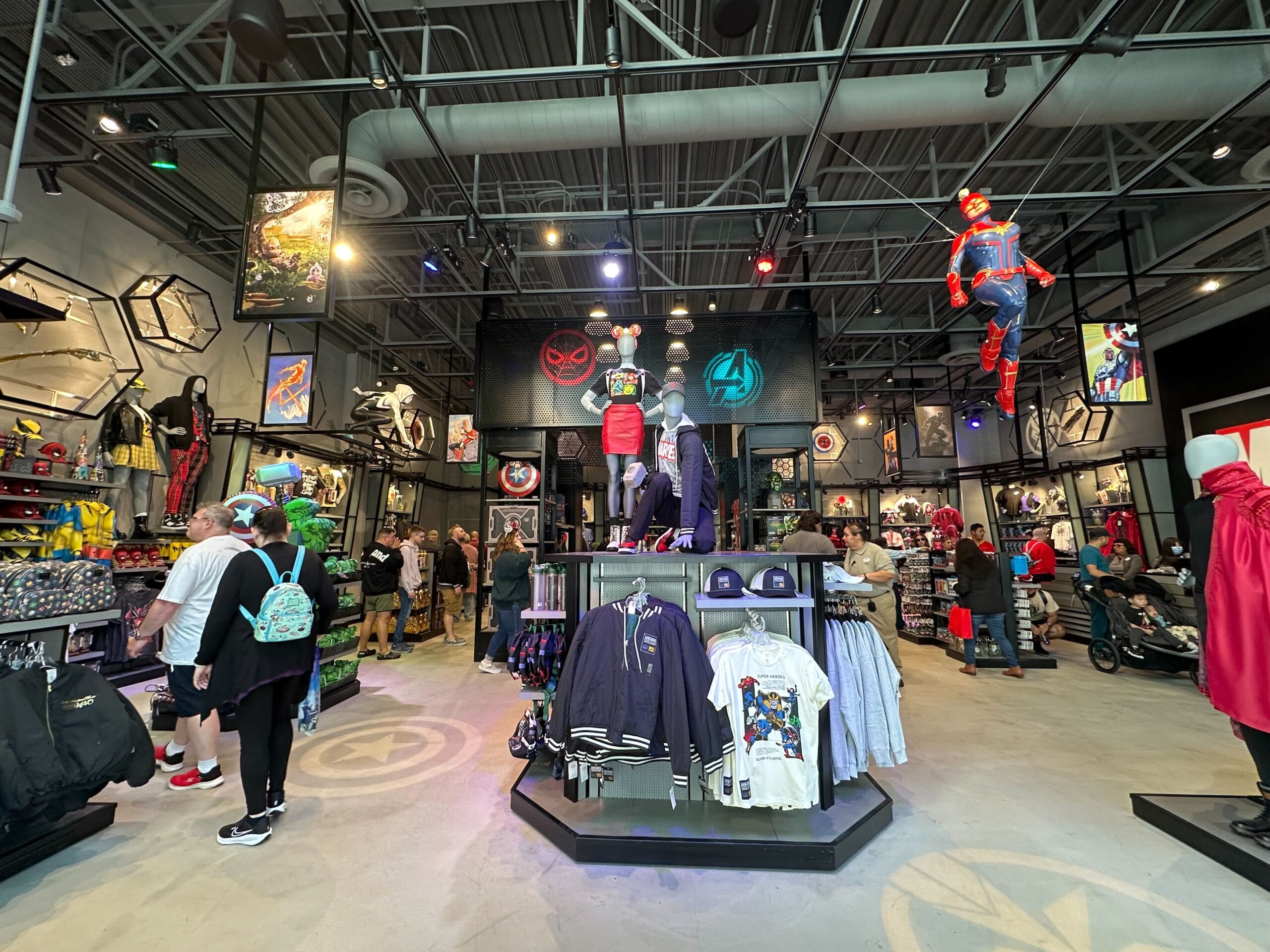 The Avengers Reserve Store in Downtown Disney boasts a chic interior filled with superhero-themed merchandise like clothing, posters, and figurines. Bright lighting accentuates the vibrant displays as eager shoppers browse the impressive collection.