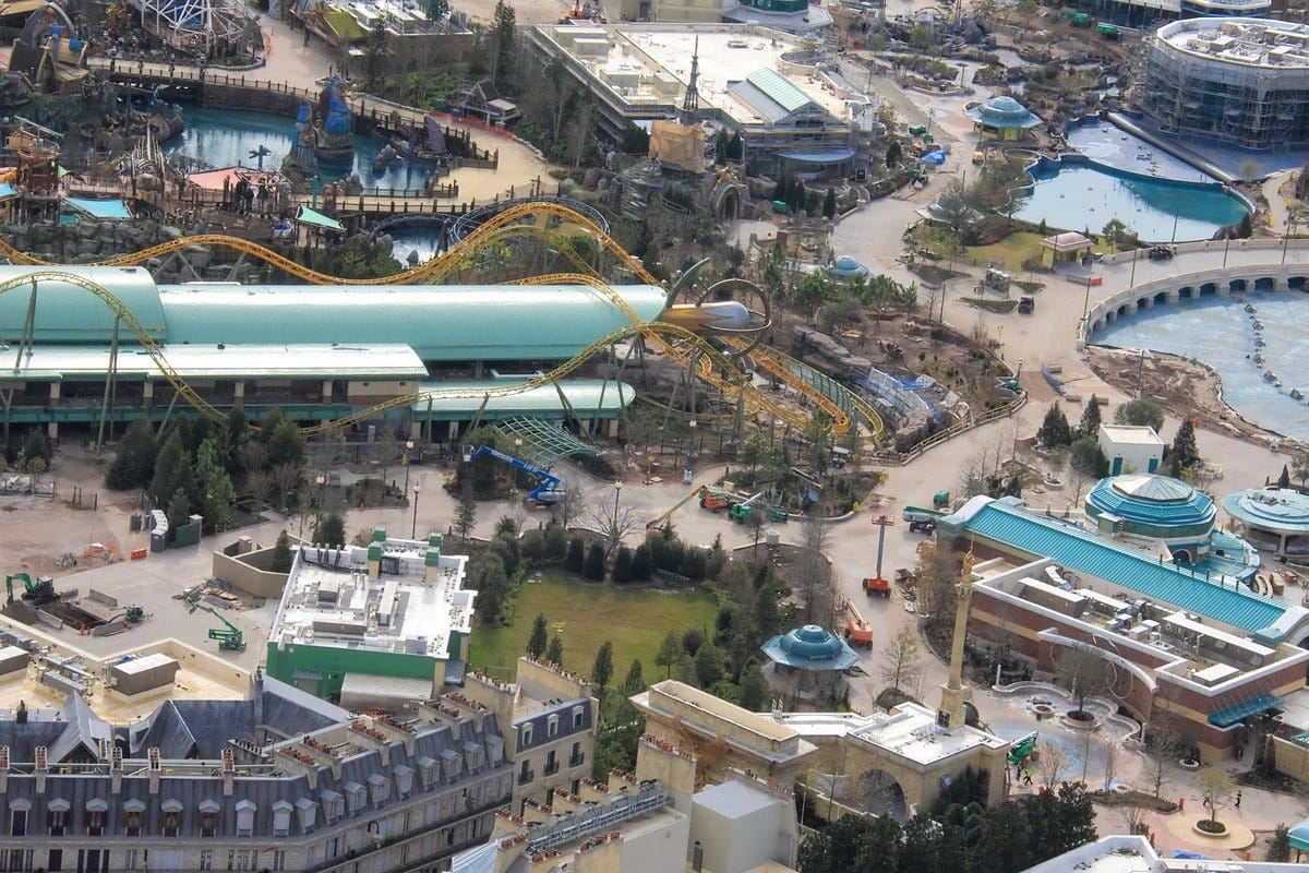 Aerial view of Epic Universe, an exciting theme park featuring roller coasters, thrilling rides, winding pathways, and vibrant buildings.