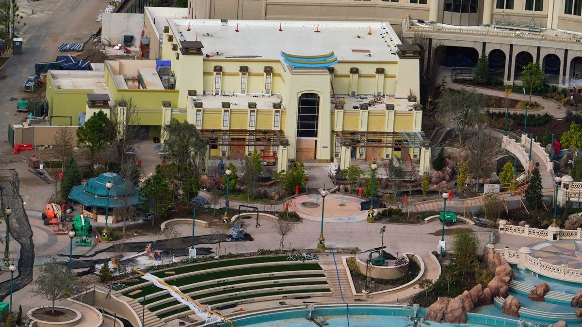 Aerial view of an epic construction site with a large building, intricate landscaping, heavy machinery, and a partially completed pool area that hints at an unfolding universe of possibilities.