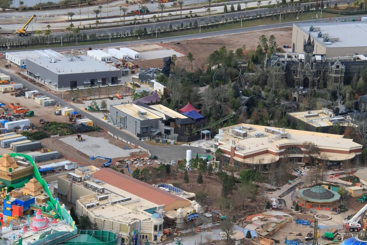 Aerial view of Epic Universe, a new theme park under construction at Universal Orlando, showcasing various buildings, pathways, and lush surrounding greenery.