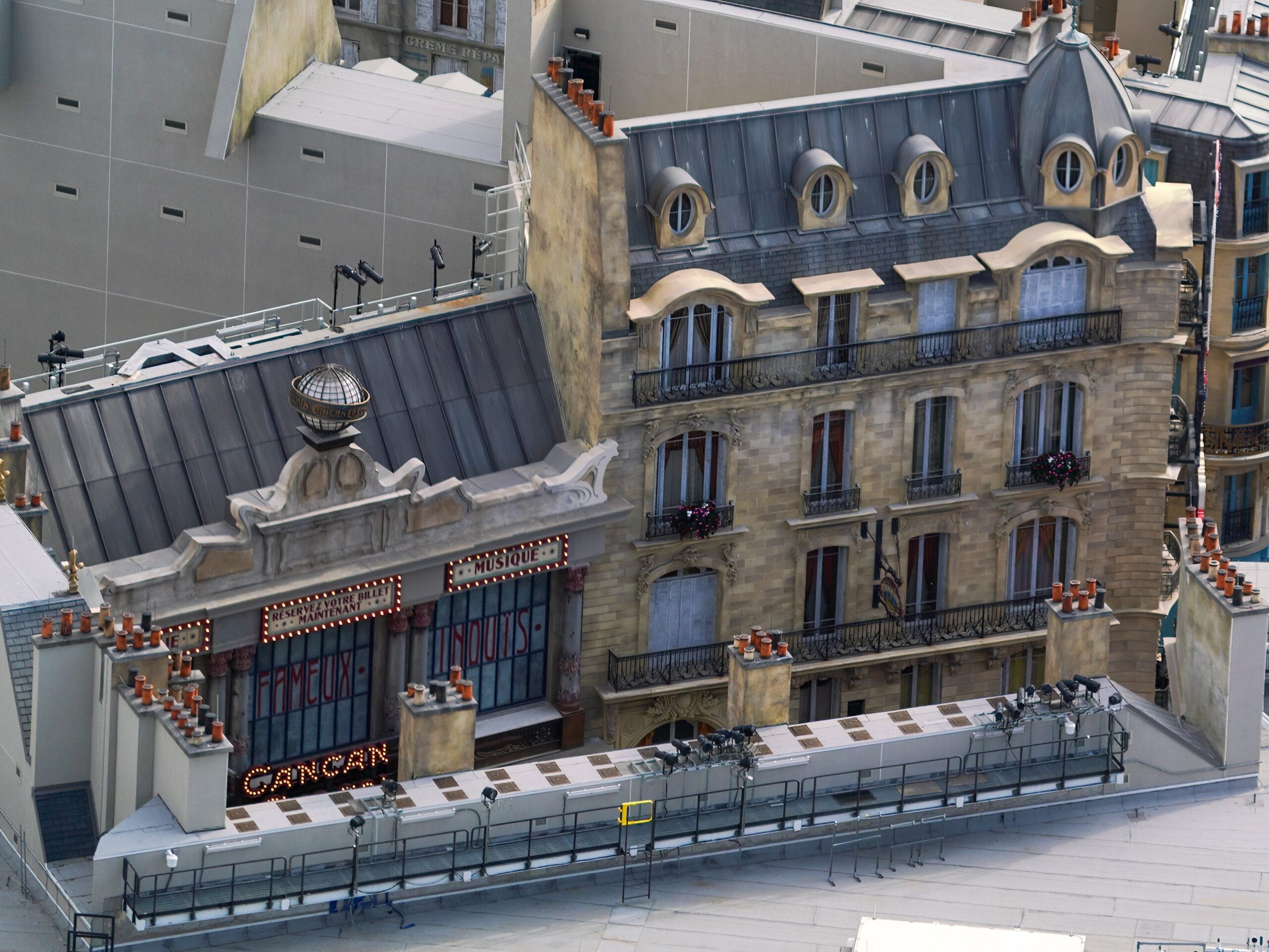 Aerial view of a historic building facade with a "Cancan" sign, featuring ornate details and multiple windows, set against a background of modern structures.