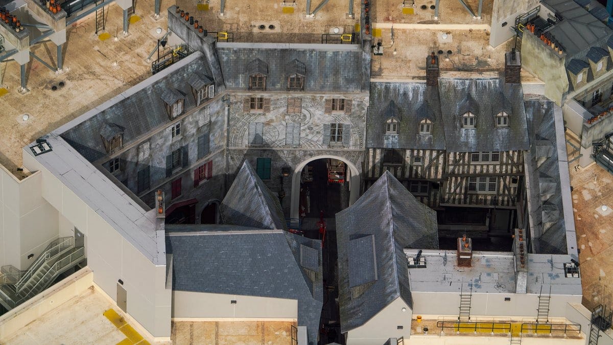 Aerial view of a building with a courtyard, featuring a mix of slate roofs and detailed stonework, surrounded by construction scaffolding and equipment.