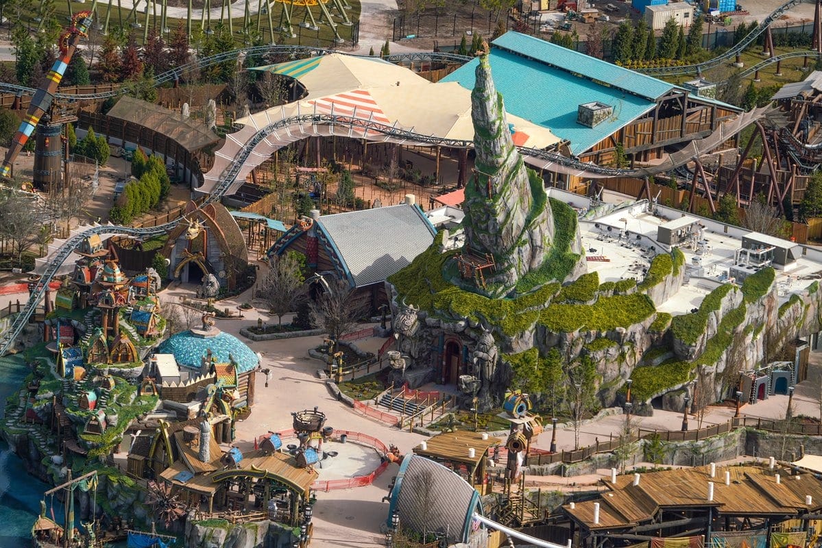 Aerial view of a theme park with a rocky, spiral centerpiece surrounded by various attractions and pathways.