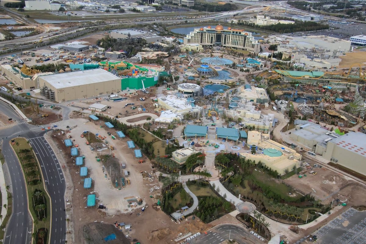 Aerial view of Epic Universe theme park under construction, showcasing unfinished buildings, winding pathways, and expansive surrounding landscaping.