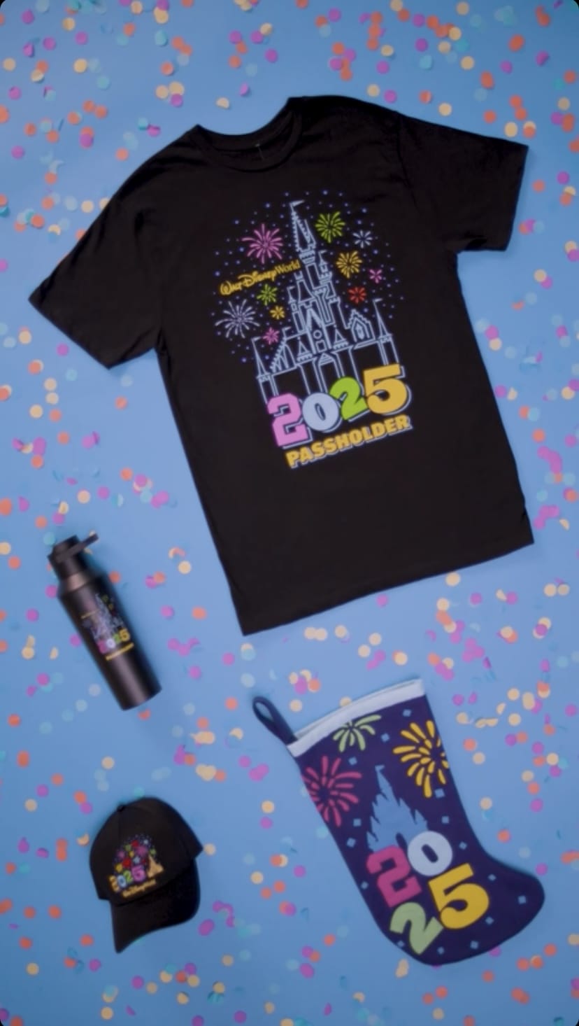Black t-shirt, water bottle, cap, and stocking each featuring colorful fireworks and "2025 Passholder" design on a blue confetti background.